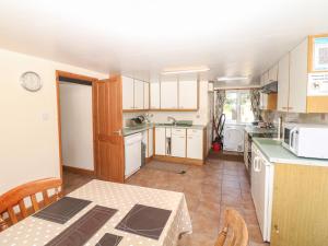 ビデフォードにあるThe Cottageの白いキャビネットとテーブル付きのキッチンが備わります。