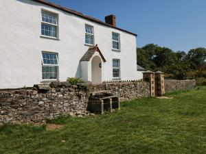 a white house with a stone wall and a fence at The Barton in Bideford