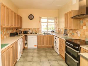 una cocina con armarios de madera y electrodomésticos blancos en The Barton, en Bideford