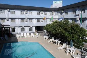 a hotel with a swimming pool and chairs and a building at Hotel Hoxon in Luján
