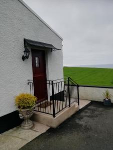 a white building with a red door and a porch at Craig Cottage Self-catering in Bushmills