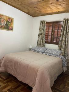 1 dormitorio con 1 cama en una habitación con ventana en Cantinho da alice, en Campos do Jordão