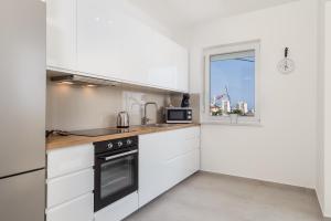 una cocina con armarios blancos y una ventana en Apartments Vila Belvedere, en Rijeka