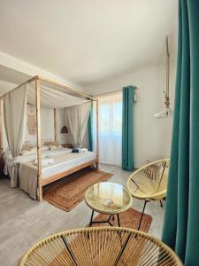 een slaapkamer met een hemelbed met stoelen en een tafel bij Faro - Conte di CapoTesta in Santa Teresa Gallura