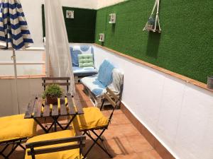 balkon ze stołem i krzesłami oraz zieloną ścianą w obiekcie Ílios Apartamentos w Maladze