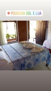 a bedroom with a bed with a blue and white quilt at Pousada e Restaurante Sol e Lua in Mucuri