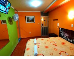 1 dormitorio con 1 cama con paredes de color naranja y TV en Sombrero de Paja en Chiclayo