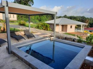 una piscina con due sedie e un padiglione di Les Balcons du Parc a Petit-Bourg