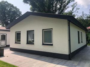 un pequeño edificio blanco con ventanas en un patio en Unique chalet in Harderwijk with large garden en Harderwijk