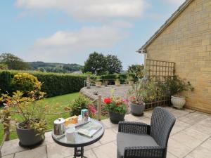a patio with a table and chairs and plants at Cuckoo Cottage in Bridport