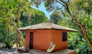 une petite maison orange avec un hamac suspendu. dans l'établissement Pousada Aldeia Banzaê, à Imbassaí