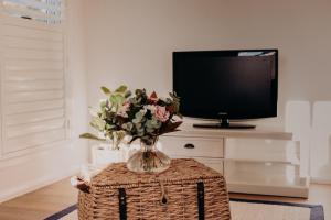 a vase of flowers on a table in front of a tv at The Red Hill Nest in Glanmire