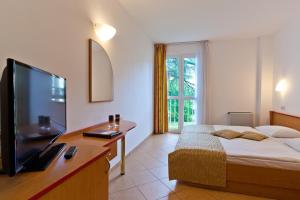 a bedroom with a bed and a flat screen tv at Villa Lovorka - Hotel Resort Dražica in Krk