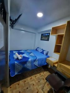 1 dormitorio con 1 cama azul y suelo de madera en Hostal Estrellas, en Huaraz