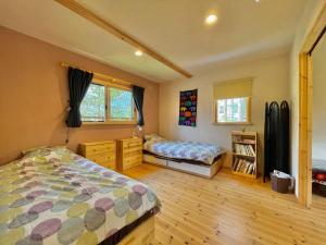 sypialnia z 2 łóżkami oraz drewnianą podłogą i oknami w obiekcie Pop Inn Hakuba w mieście Hakuba