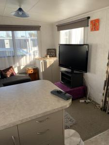 a living room with a flat screen tv and a kitchen at Te Puru B8 - 2 bedroom chalet in Te Puru
