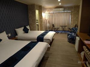 Habitación de hotel con 2 camas y mesa en Guan Lun Hotel en Hualien