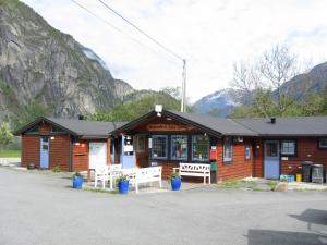 a building with two benches in front of it with mountains at Sæbø Camping in Eidfjord
