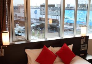 a couch with red pillows in a room with windows at Daiwa Roynet Hotel Okayama Ekimae in Okayama