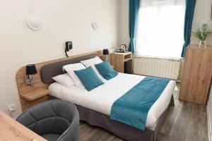 a bedroom with a large bed with blue pillows at Azur Hotel in Balaruc-les-Bains