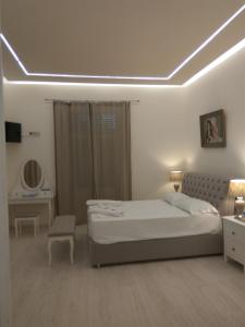 a white bedroom with a bed and a table at NAFPAKTOS Beach luxury Suites in Nafpaktos