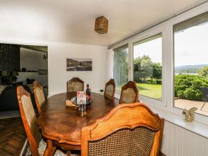 a dining room with a table and chairs and windows at Corranbuie in Tarbert