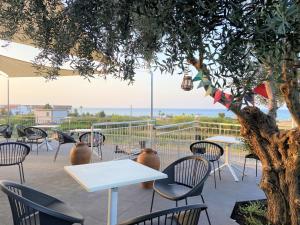 un patio con mesas, sillas y un árbol en Egò Marine, en Mandatoriccio Marina