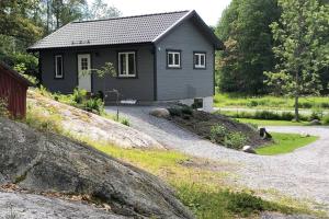 una pequeña casa negra en un camino de grava en Cottage perfect for short time rent, en Gustavsberg