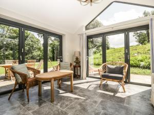 uma sala de estar com uma mesa e cadeiras e janelas grandes em Hillside Cottage em Shaftesbury