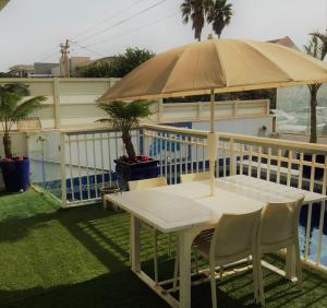 uma mesa e cadeiras debaixo de um guarda-sol ao lado de uma piscina em Jasmin 4 em Netanya