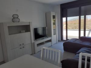 Una sala de estar con un sofá y un televisor. en Atico Casa Kyara, con gran Terraza y Parking, Iceberg Albacerrado, en Tarifa