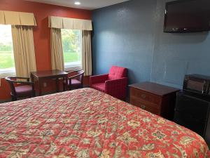 um quarto de hotel com uma cama e uma cadeira e janela em Kenwood Court Motel em Wilson