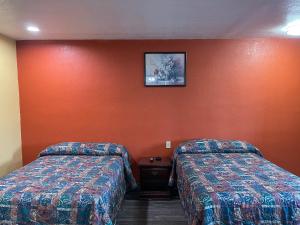 duas camas num quarto de hotel com paredes cor de laranja em Kenwood Court Motel em Wilson