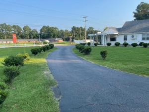 a road in front of a house with bushes at Kenwood Court Motel in Wilson