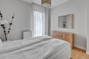 a white bedroom with a large bed and a mirror at Luxury Bianco Apartament in Sopot