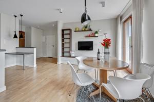 a dining room with a table and white chairs at Luxury Bianco Apartament in Sopot