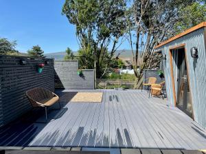 una terraza de madera con un banco y sillas. en Stylish, central studio with kitchen & large deck, en Fort William