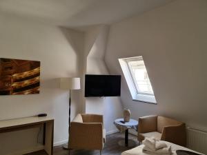 uma sala de estar com duas cadeiras e uma televisão em Cityappartement am Theaterplatz em Weimar