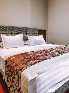 a large bed with a brown and white blanket on it at Hotel Kompleksi Arifi in Shkodër