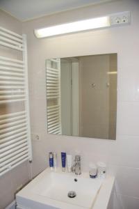 een witte badkamer met een wastafel en een spiegel bij Fries Vakantiehuis, grote tuin, nabij het Pikmeer in Grou