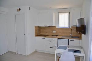 a kitchen with white cabinets and a table and a tv at Les Forges studio étage in Avoine