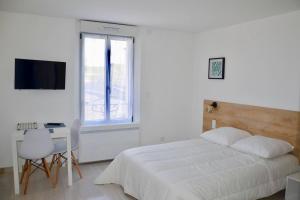 a bedroom with a bed and a desk and a television at Les Forges studio étage in Avoine