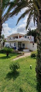 a large white house with a palm tree in a yard at Villa Priscilla in Cinisi