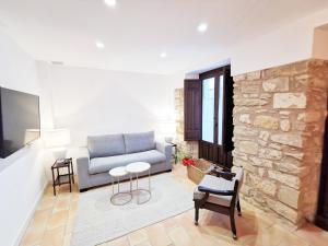 a living room with a couch and a stone wall at Apartamentos Tres Llaves Palacio de Vela de los Cobos in Úbeda