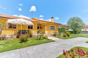 a yellow house with a patio and an umbrella at Finca Victoriana Riaza in Riaza