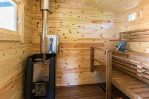 Habitación con paneles de madera y estufa en una cabaña. en Upea hiekkaranta mökki, en Ähtäri