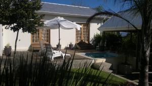 a house with a swimming pool and an umbrella at B&B on Church in Oudtshoorn
