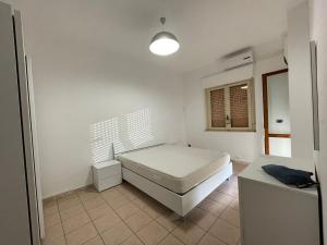 een witte kamer met een bed en een raam bij Casa Mana in Scalea