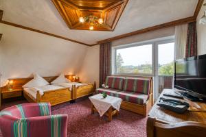 ein Hotelzimmer mit einem Bett, einem Sofa und einem Fenster in der Unterkunft Hotel Haus Tiefenbach in Büllingen