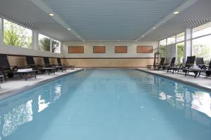 een groot zwembad met stoelen en tafels in een gebouw bij Ringhotel Posthotel Usseln in Willingen